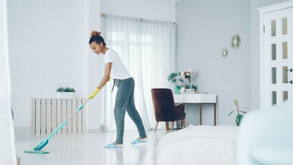 A cleaner mopping the floor of a bright living room
